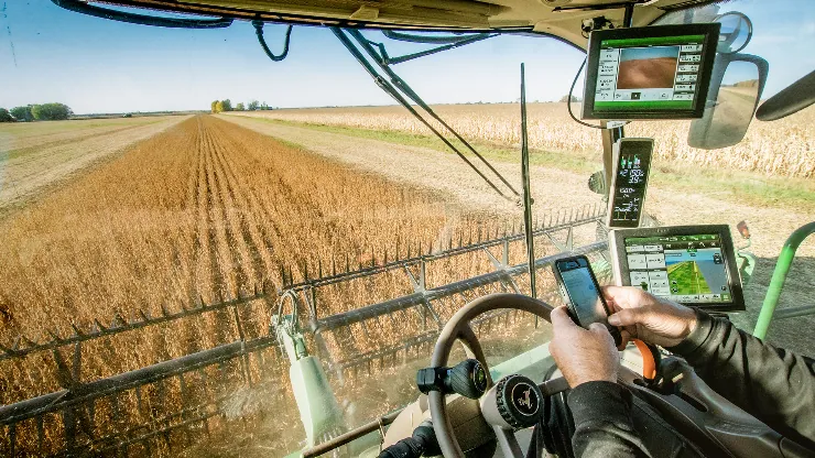 An image of a person using digital devices on agricultural equipment.